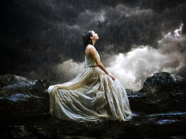 woman in white in storm on moutain rocks